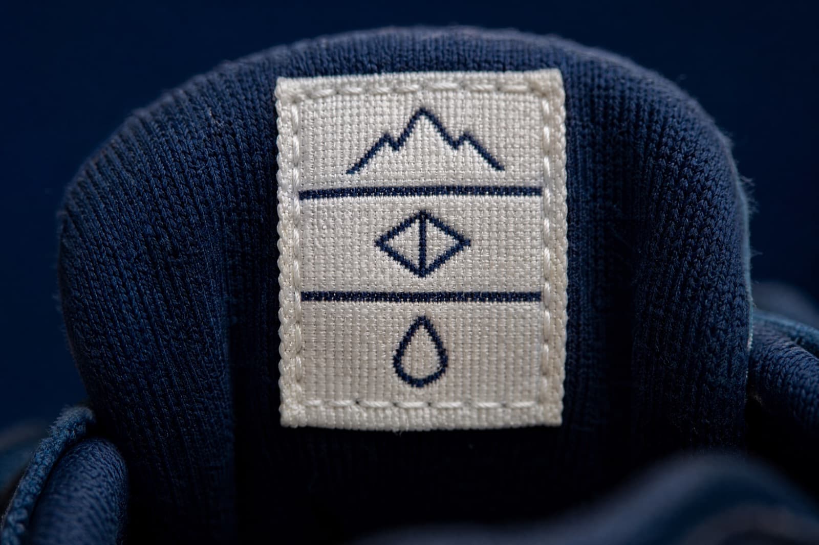 Macro photograph of a stitched fabric label inside a shoe showing three rows of pictogram symbols